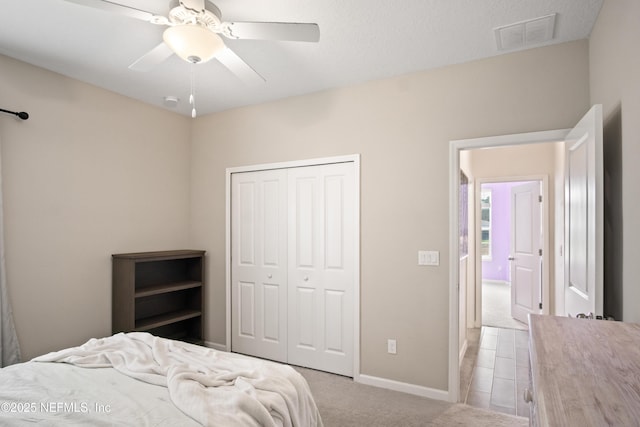 bedroom featuring light carpet, ceiling fan, and a closet