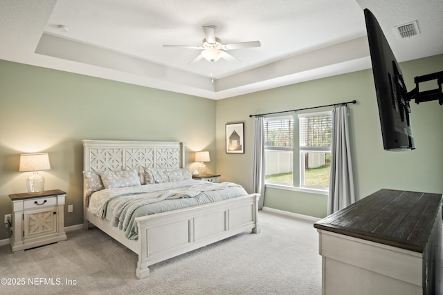 carpeted bedroom with ceiling fan and a raised ceiling