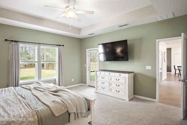 bedroom with ceiling fan, a raised ceiling, light carpet, and access to exterior