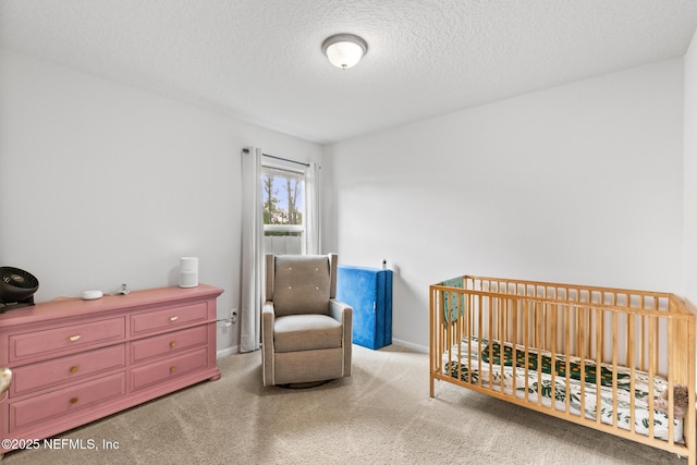 carpeted bedroom featuring a crib, a textured ceiling, and baseboards