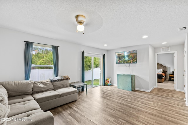 living room with visible vents, light wood-style flooring, and plenty of natural light
