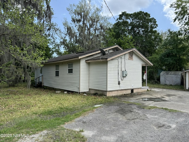 4504 Clairmont Rd, Jacksonville, FL 32207 - view of side of home featuring an outbuilding, roof with shingles, and aphalt driveway