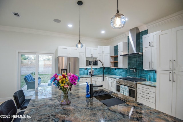 kitchen with dark stone countertops, high end appliances, white cabinetry, decorative light fixtures, and wall chimney exhaust hood