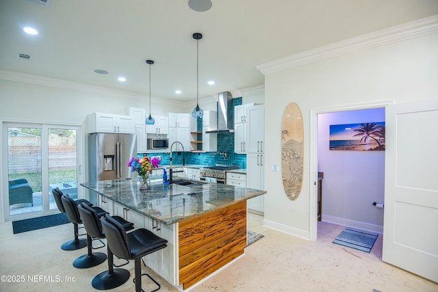 kitchen with dark stone countertops, high quality appliances, wall chimney range hood, white cabinets, and a breakfast bar area