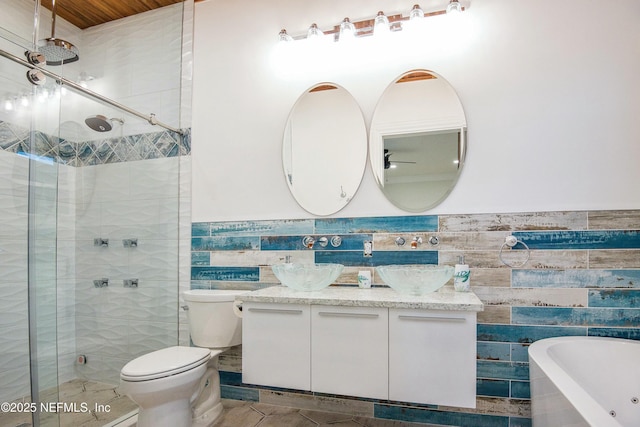 full bathroom featuring independent shower and bath, tile walls, vanity, toilet, and tile patterned floors