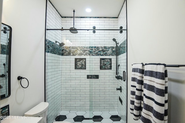 bathroom featuring tiled shower and toilet