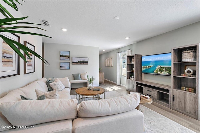 living room featuring recessed lighting, visible vents, a textured ceiling, and light wood-style flooring