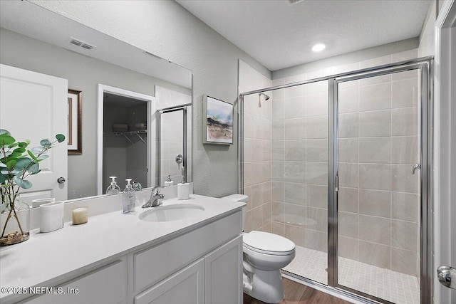 full bath with visible vents, toilet, a stall shower, wood finished floors, and vanity