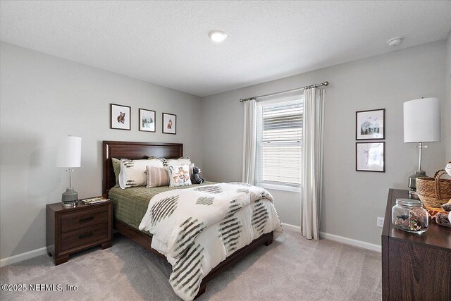 bedroom with light colored carpet, baseboards, and a textured ceiling