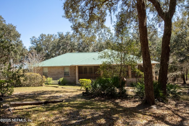 exterior space with covered porch, metal roof, and brick siding