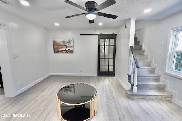 entrance foyer featuring a ceiling fan, light wood-type flooring, stairway, and a barn door