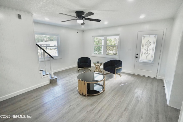 sitting room featuring a textured ceiling, stairway, wood finished floors, and baseboards