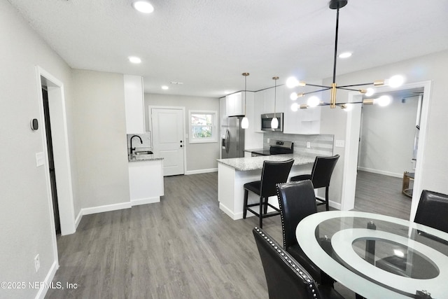 dining room with a chandelier, recessed lighting, baseboards, and wood finished floors