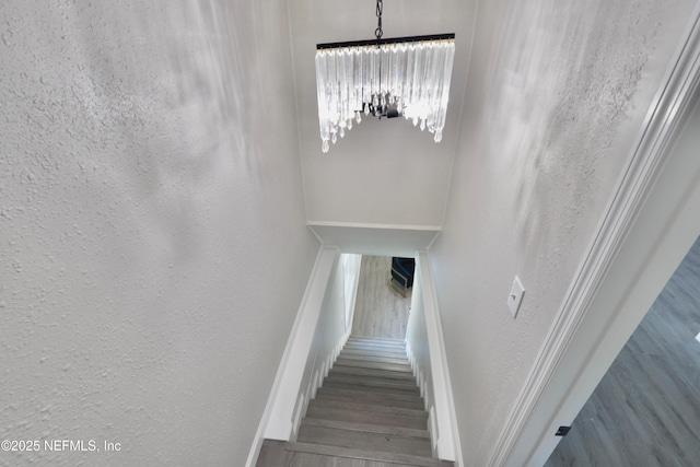 stairs with a textured wall, wood finished floors, and baseboards