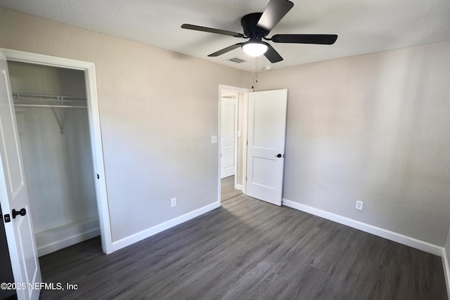 unfurnished bedroom featuring a ceiling fan, visible vents, baseboards, a closet, and dark wood finished floors