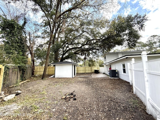 view of yard with an outbuilding, a storage unit, cooling unit, and a fenced backyard