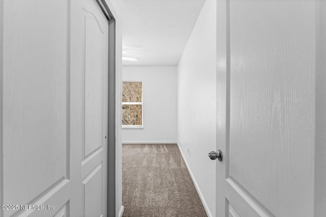 hallway featuring carpet and baseboards