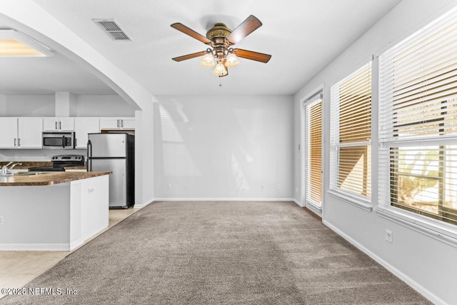 kitchen featuring dark countertops, visible vents, appliances with stainless steel finishes, white cabinetry, and light carpet