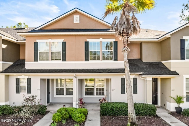 townhome / multi-family property with a shingled roof and stucco siding