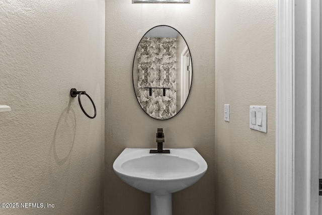 bathroom with a textured wall and a sink