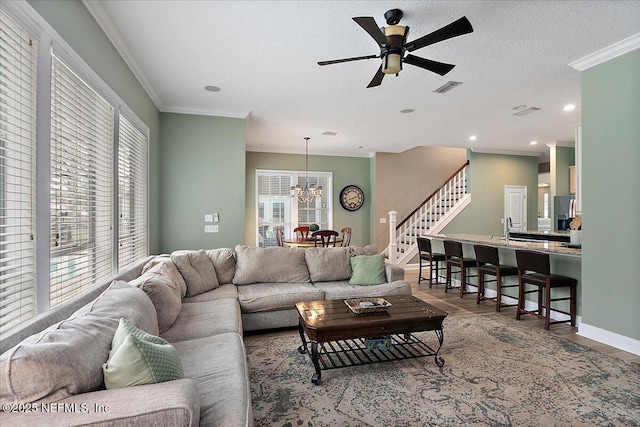 living area with ornamental molding, a wealth of natural light, visible vents, and stairway