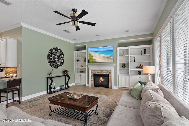 living area with light wood-style floors, visible vents, and crown molding