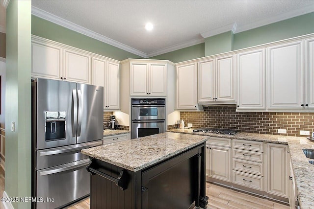 kitchen featuring light stone counters, a center island, backsplash, appliances with stainless steel finishes, and white cabinetry