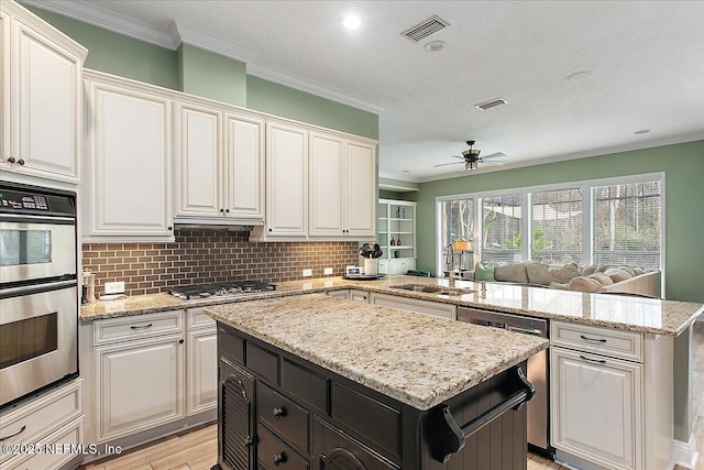 kitchen with stainless steel appliances, a sink, white cabinetry, and a center island