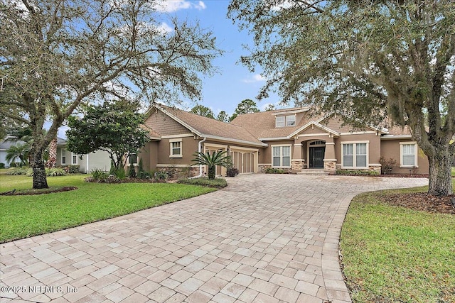 craftsman house featuring stone siding, decorative driveway, an attached garage, and stucco siding