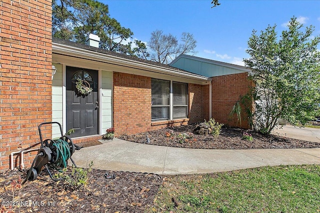 doorway to property featuring brick siding and a chimney