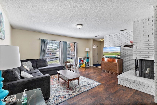 living area with visible vents, a fireplace, a textured ceiling, and wood finished floors