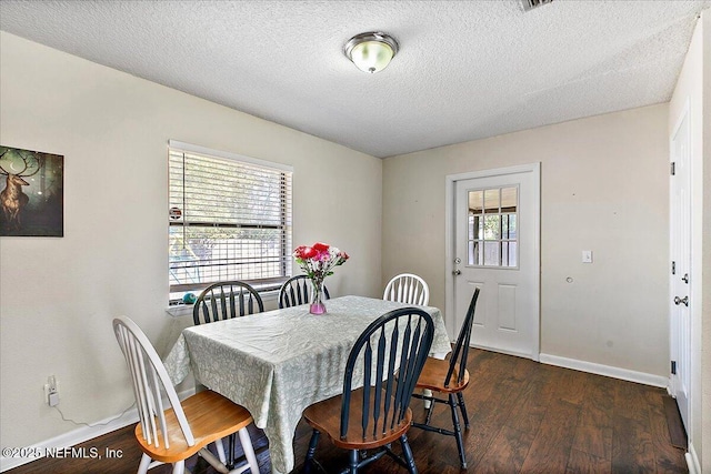 dining area featuring a textured ceiling, dark wood-type flooring, and baseboards