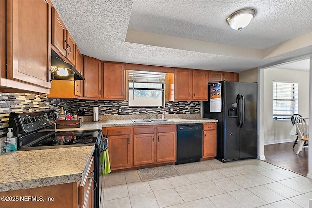 kitchen featuring a healthy amount of sunlight, black appliances, brown cabinets, and a sink