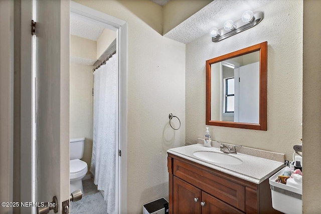 bathroom with a textured wall, vanity, and toilet