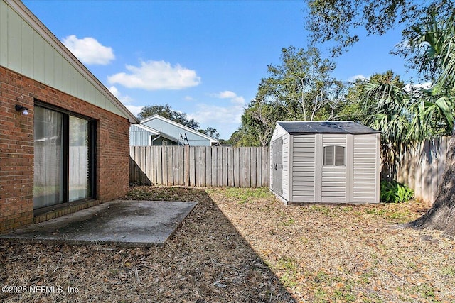 view of yard with an outbuilding, a shed, a patio area, and a fenced backyard