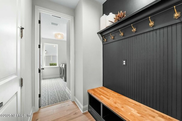 mudroom with visible vents, light wood-style flooring, baseboards, and separate washer and dryer