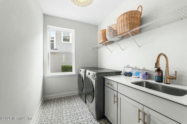 washroom with light tile patterned flooring, a sink, baseboards, washer and dryer, and cabinet space