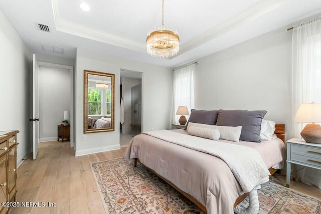 bedroom with light wood finished floors, a tray ceiling, visible vents, and a notable chandelier