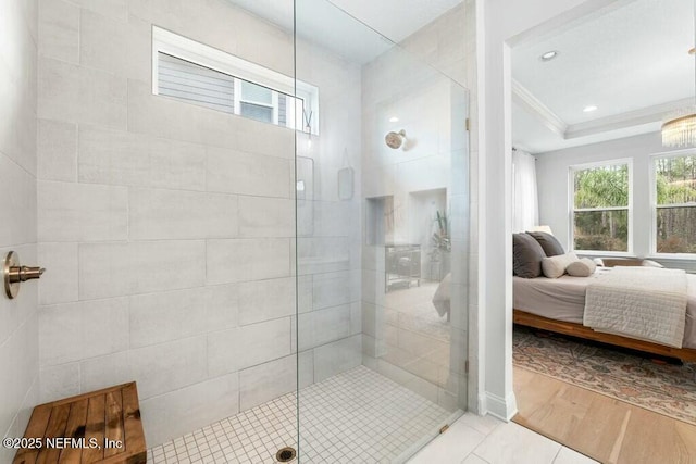 ensuite bathroom featuring crown molding, a healthy amount of sunlight, connected bathroom, wood finished floors, and tiled shower