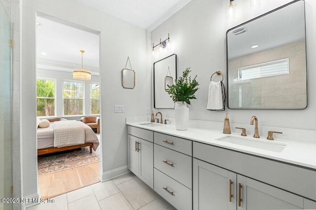 ensuite bathroom featuring a sink, double vanity, connected bathroom, and tile patterned floors