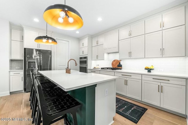 kitchen featuring pendant lighting, light countertops, a breakfast bar area, and stainless steel appliances