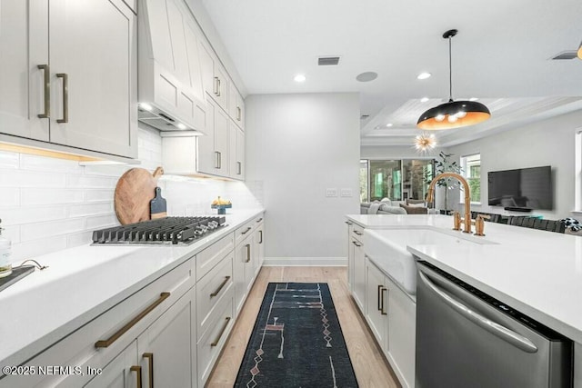 kitchen with appliances with stainless steel finishes, open floor plan, decorative light fixtures, light countertops, and light wood-type flooring