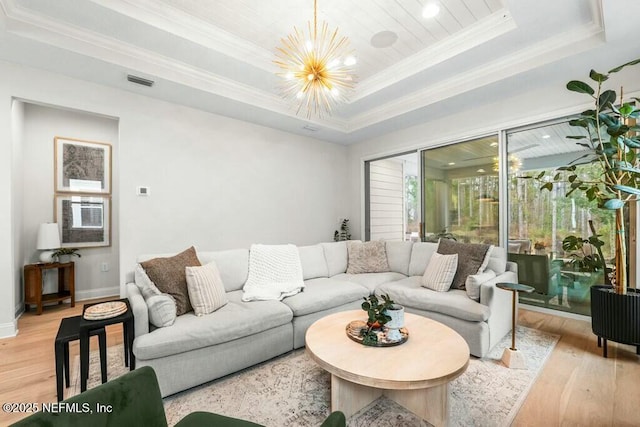 living room with light wood finished floors, visible vents, a raised ceiling, crown molding, and a chandelier