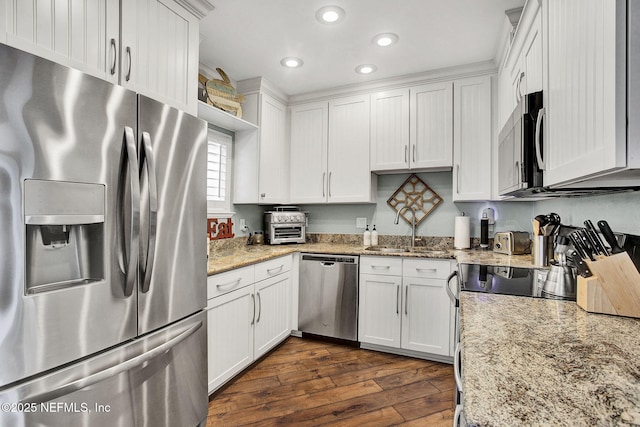 kitchen with light stone counters, a sink, white cabinetry, appliances with stainless steel finishes, and dark wood finished floors