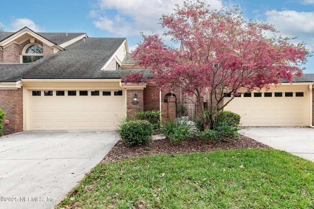 view of front facade featuring a garage, concrete driveway, brick siding, and roof with shingles