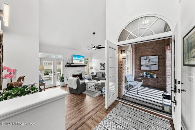 entryway featuring a lit fireplace, french doors, wood finished floors, and a towering ceiling