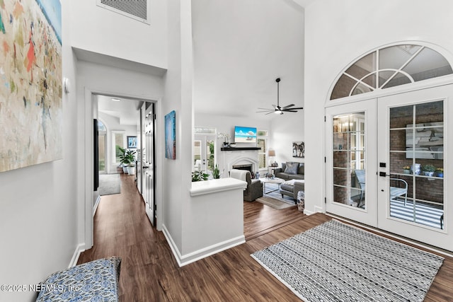 hall with french doors, visible vents, a towering ceiling, dark wood-type flooring, and baseboards