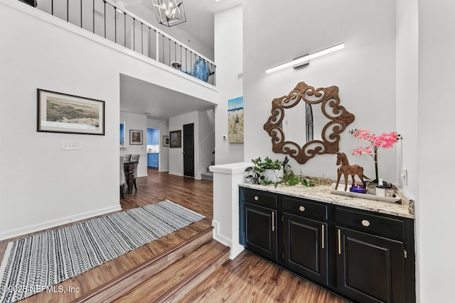 interior space featuring baseboards, stairway, a high ceiling, and wood finished floors