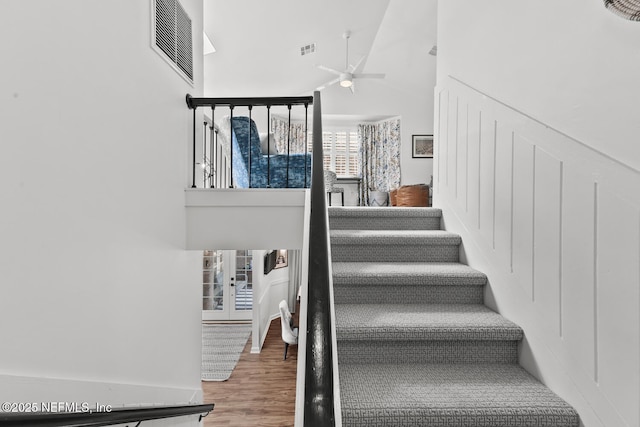 stairway featuring visible vents, a high ceiling, and wood finished floors