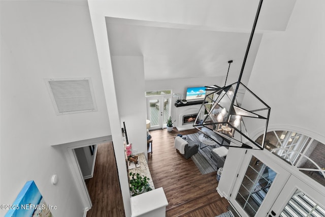 living room with dark wood-type flooring, visible vents, and a lit fireplace